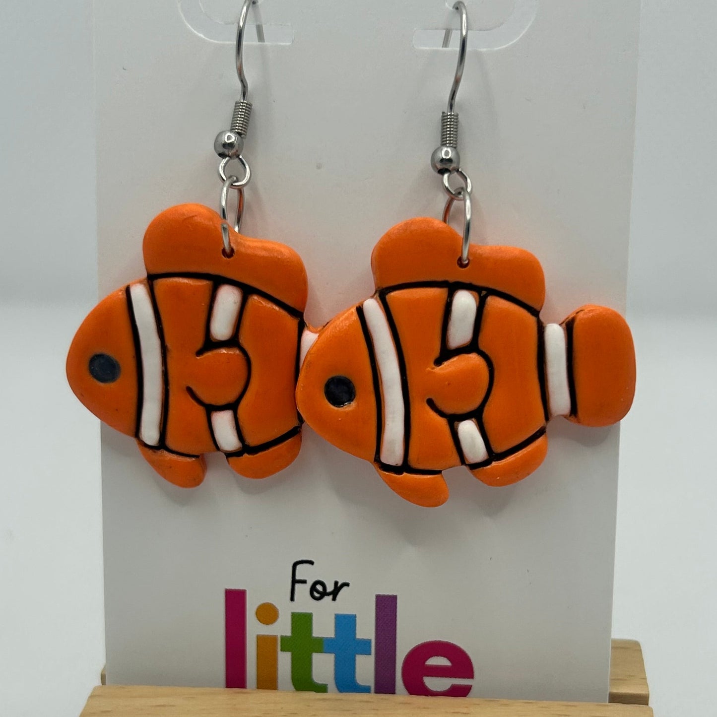 Orange, black and white clownfish earrings on a display card with 'For little lobes' text.