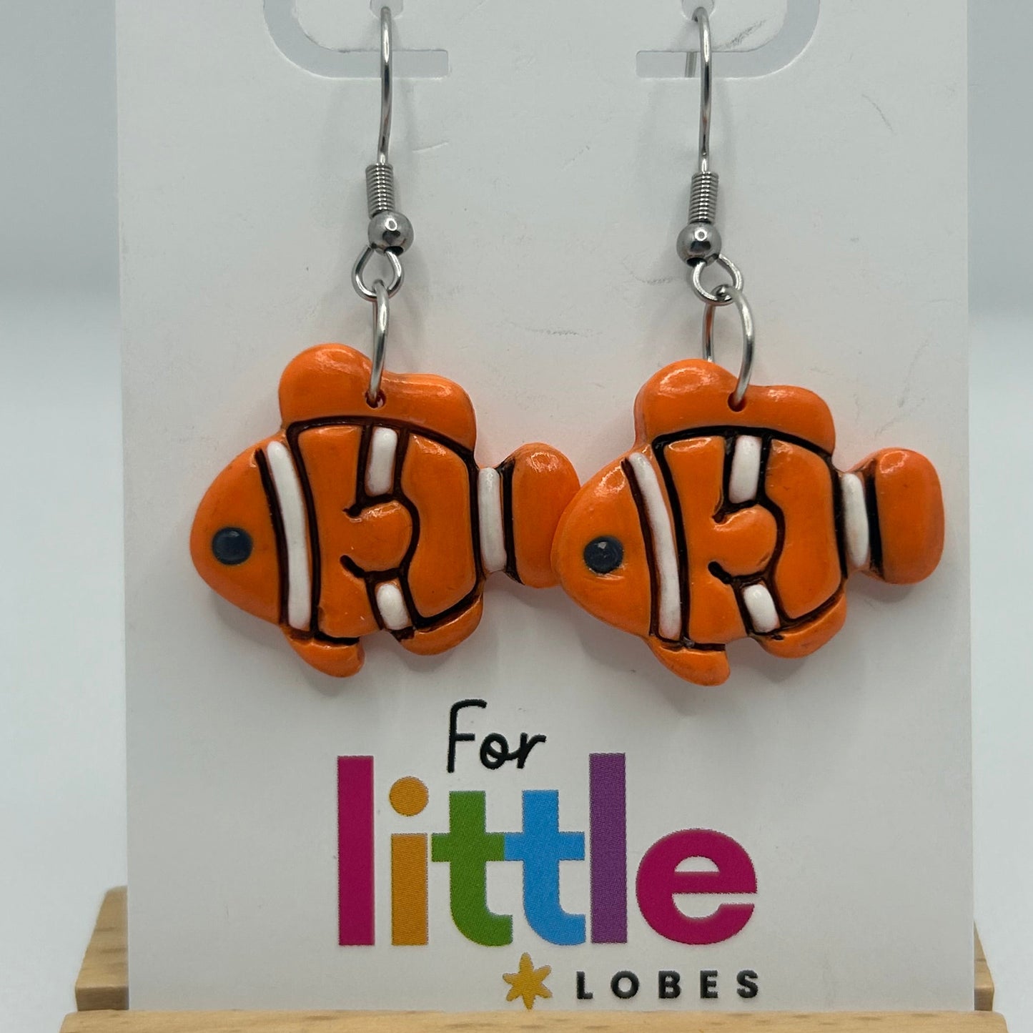 Orange, black and white clownfish earrings on a display card with 'For little lobes' text.