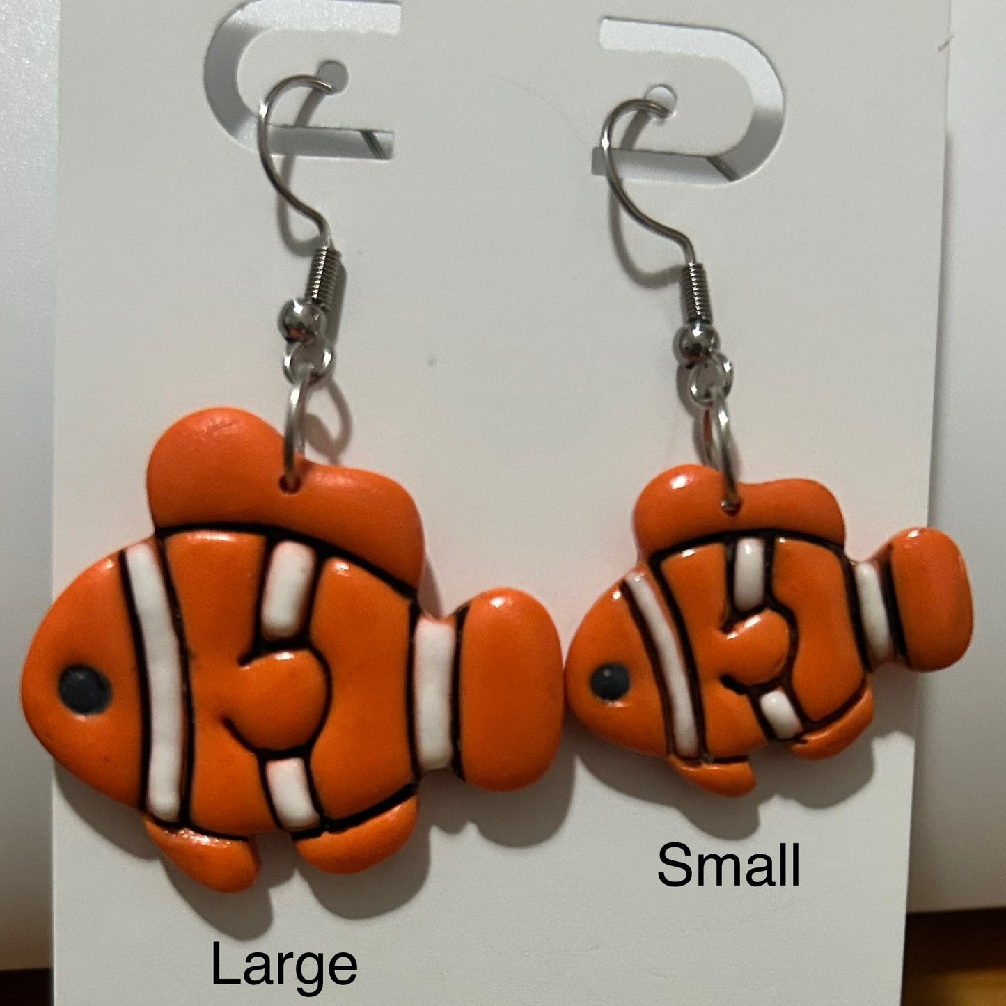 Pair of clownfish-shaped earrings on a display card with 'Large' and 'Small' labels.