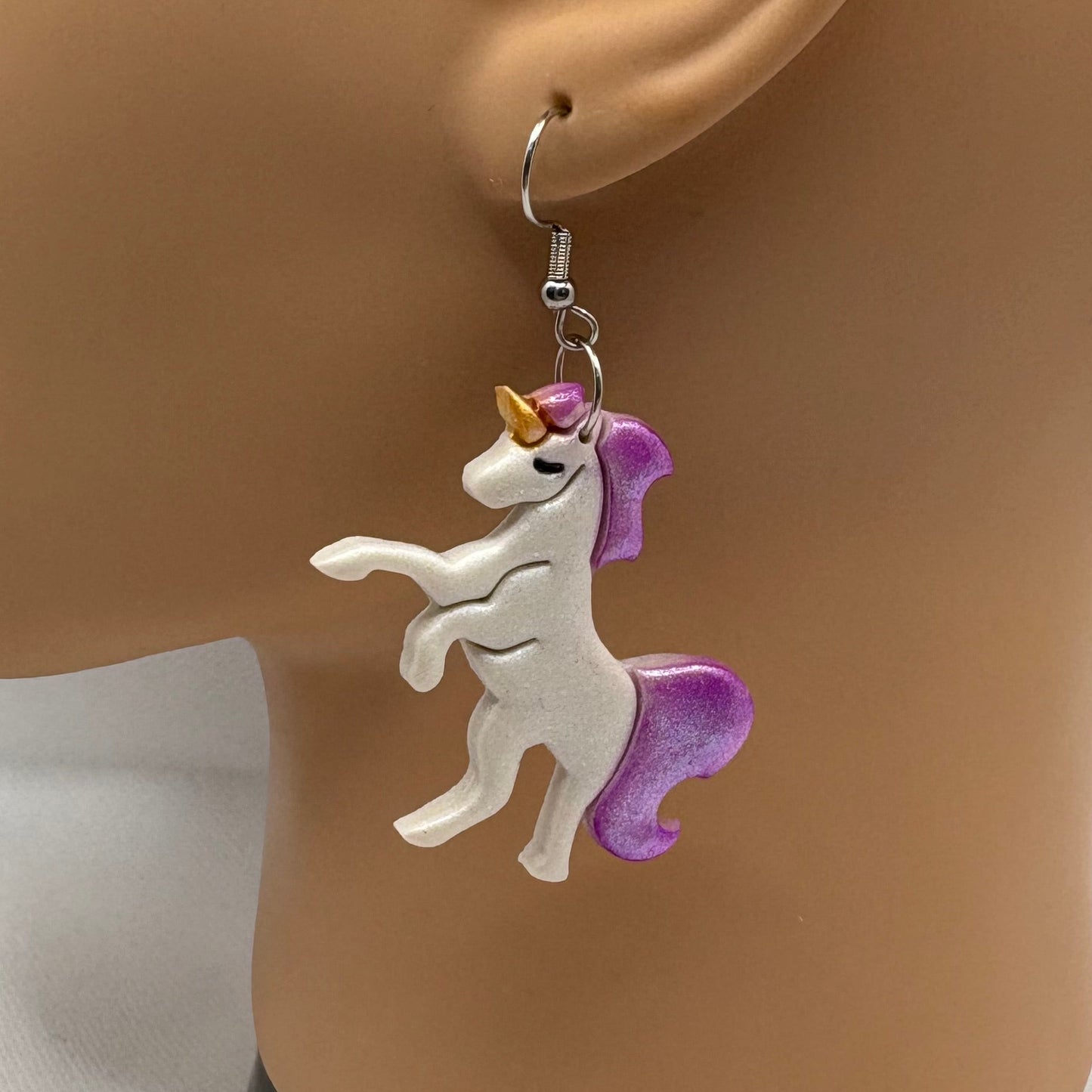 Unicorn-shaped earring on a mannequin ear with a white background