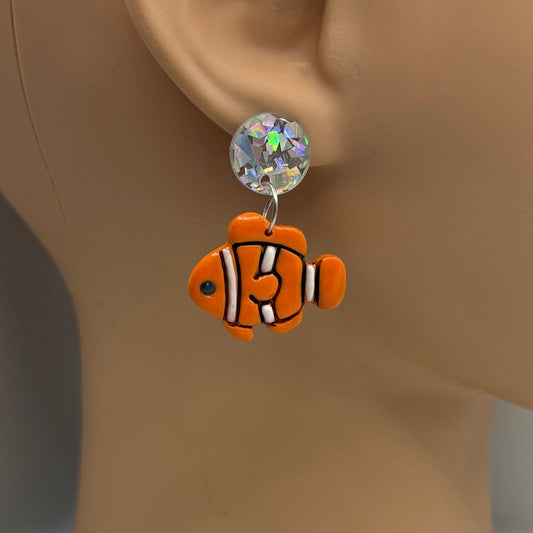 Orange, black and white clownfish earring hanging from the ear of a mannequin head.