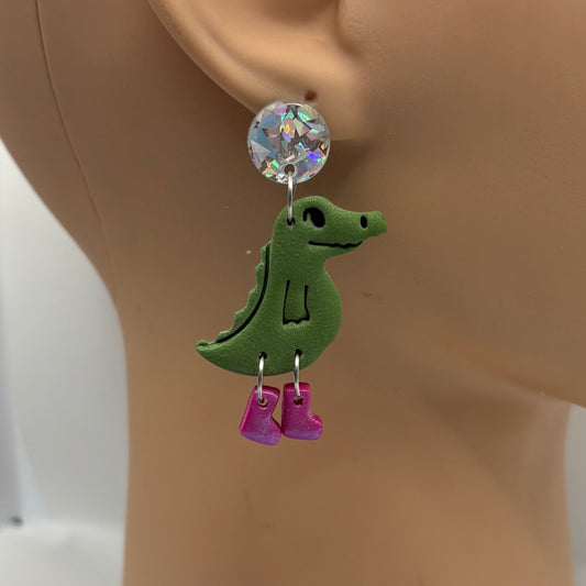 Green crocodile-shaped earrings with purple gumboots on a mannequin head.