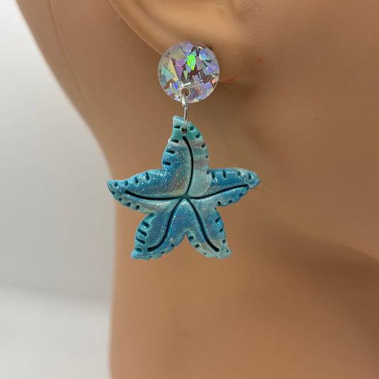 Blue starfish earring on a mannequin ear against a white background