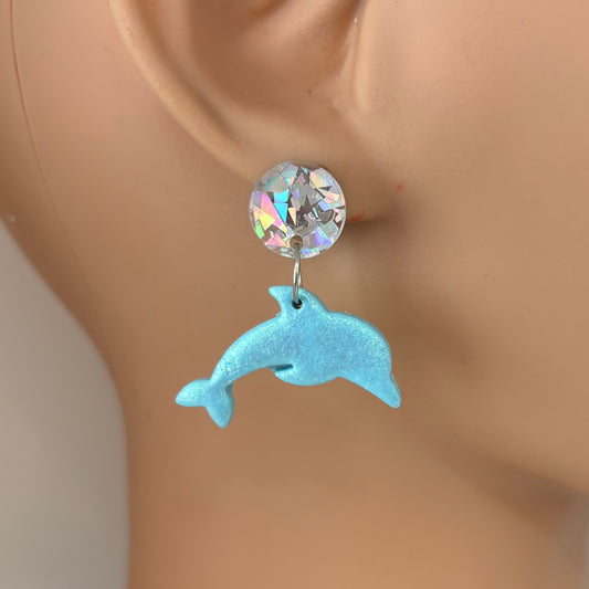 Earring with a crystal and dolphin design on a mannequin ear.
