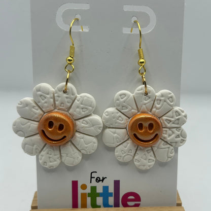 Flower-shaped earrings with smiley faces on a display card.