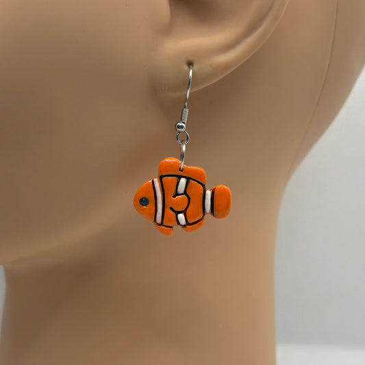 Orange, black and white clownfish earring hanging from the ear of a mannequin head.