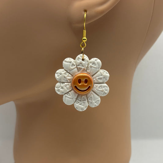 White flower-shaped earring with a smiley face on a mannequin ear.