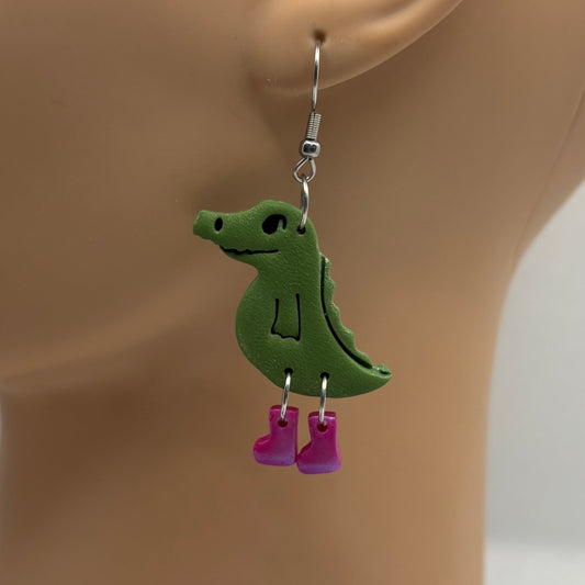 Green crocodile-shaped earrings with purple gumboots on a mannequin head.