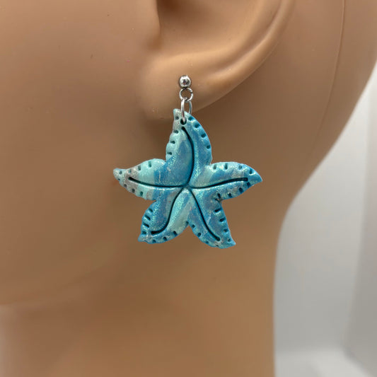 Blue starfish earring on a mannequin ear against a white background