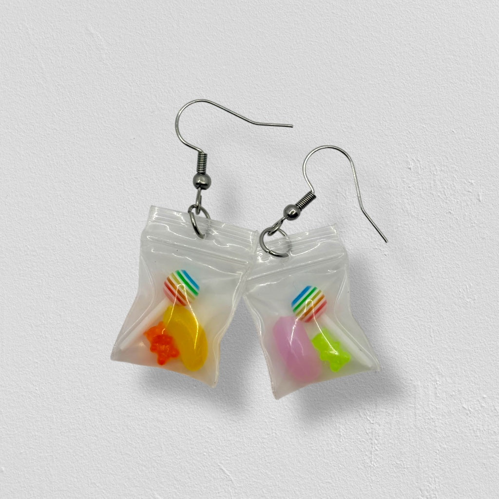 Earrings shaped like small bags with colorful candy contents on a white background