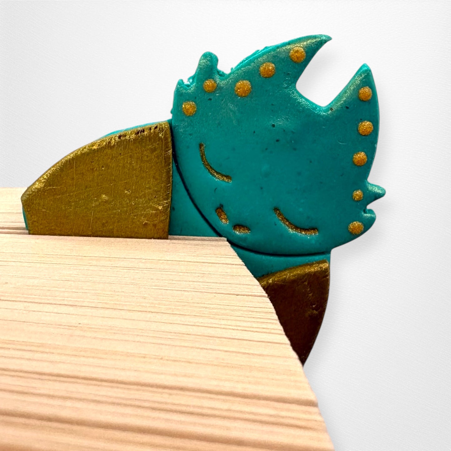 Teal and gold dragon-shaped bookmark on a white background